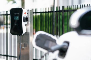 Kamu parkındaki EV şarj prizine bağlı bulanık elektrikli araçla CO2 emisyonunu azaltmak için sürdürülebilir ve yenilenebilir enerji ile çalışan odaklanma istasyonu.