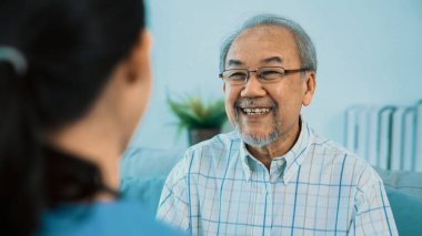 A young female doctor inquires about personal information of a contented senior at home. Medical care for the elderly, elderly illness, and nursing homes, home care.