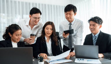 Harmony in office concept as business people analyzing dashboard paper together in workplace. Young colleagues give ideas at manager desk for discussion or strategy planning about project.