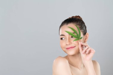 Closeup glamorous beautiful woman with soft make up and flawless smooth clean skin holding green leaf. Cannabis skincare cosmetic product for natural skin treatment concept in isolated background