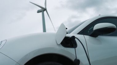 Çevreyi korumak için rüzgar türbininden yeşil ve yenilenebilir enerjiyle çalışan şarj istasyonunda şarj edilen gelişmiş gelecek enerji altyapısı konsepti.