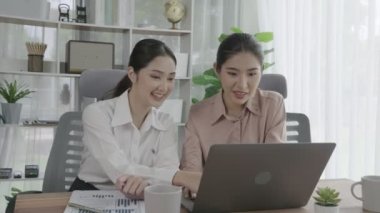 Ofis çalışma alanında birlikte çalışan iki genç hevesli iş kadını. Genç meslektaşlar tartışırken ve dizüstü bilgisayar kullanırken. Modern ofis çalışanları masada birlikte oturuyorlar..