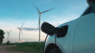 Çevreyi korumak için rüzgar türbininden yeşil ve yenilenebilir enerjiyle çalışan şarj istasyonunda şarj edilen gelişmiş gelecek enerji altyapısı konsepti.