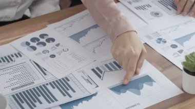 Ofis masasında çalışan iki hevesli genç iş kadını, veri tablosu raporlarıyla birlikte. Genç meslektaşlar istatistik veri kağıdı planları ve stratejisini tartışıyor ve analiz ediyorlar.