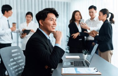 Portrait of focus young successful confident male manager, executive wearing business wear in harmony office arm crossed with blurred meeting background of colleagues, office worker.