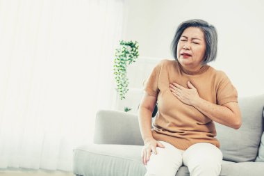 An agonizing elderly woman is experiencing chest pain. Medical attention, senior care service.