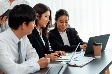 Harmony in office concept as business people analyzing dashboard paper together in workplace. Young colleagues give ideas at manager desk for discussion or strategy planning about project.