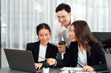 Harmony in office concept as business people analyzing dashboard paper together in workplace. Young colleagues give ideas at manager desk for discussion or strategy planning about project.