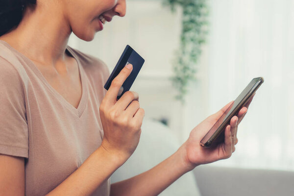 Contented young woman eagerly makes an online purchase using her smartphone. E-commerce business, online purchasing.