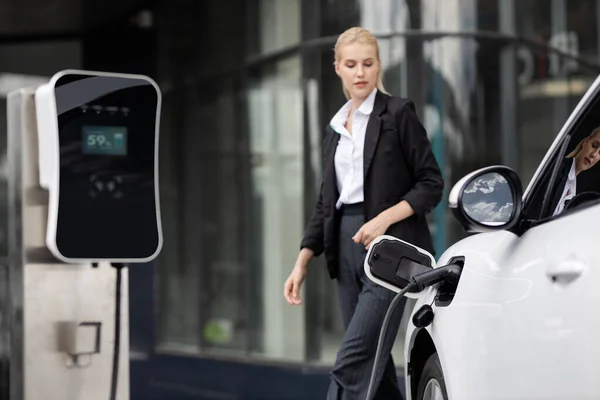 Focus Publieke Oplaadstation Voor Elektrische Auto Met Wazig Progressieve Zakenvrouw — Stockfoto