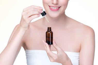 Closeup personable portrait of beautiful woman applying essential oil bottle for skincare product. Cannabis extracted CBD oil dropper for treatment and cannabinoids concept in isolated background.