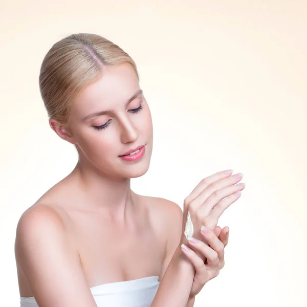 stock image Personable woman applying moisturizer cream on her hand for perfect skincare treatment concept in isolated background. Beauty care cream applying on body by female model with soft natural makeup.