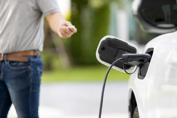 Ev車の人間を背景に 充電ステーションから屋外で電気自動車を充電することに焦点を当ててください 車のための緑と再生可能エネルギーの新しい進歩的な技術のための概念 — ストック写真