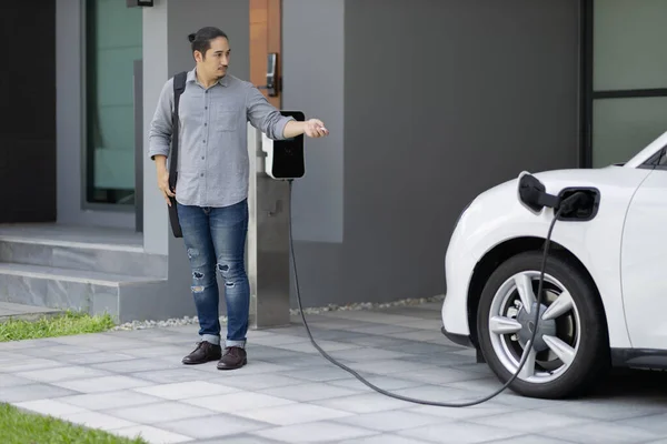 Progressive Asian Man Electric Car Home Charging Station Concept Use — Foto de Stock