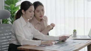 Ofis çalışma alanında birlikte çalışan iki genç hevesli iş kadını. Genç meslektaşlar tartışırken ve dizüstü bilgisayar kullanırken. Modern ofis çalışanları masada birlikte oturuyorlar..