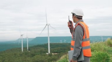 Kırsal kesimdeki bir tepenin tepesinde ya da dağda rüzgar çiftliğinde çalışan bir mühendis. Yenilenebilir ve sürdürülebilir enerjinin gelecekteki üretimi için yenilikçi bir ideal. Rüzgar türbininden enerji üretimi.