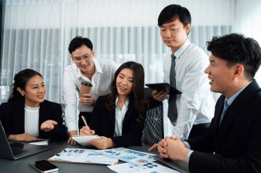 Harmony in office concept as business people analyzing dashboard paper together in workplace. Young colleagues give ideas at manager desk for discussion or strategy planning about project.