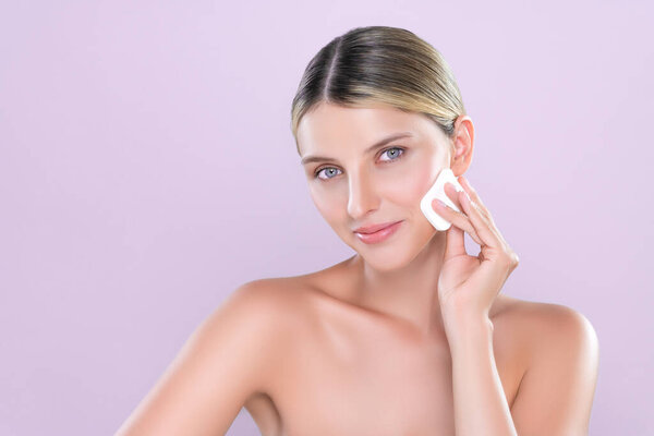 Alluring beautiful female model applying powder puff for facial makeup concept. Portrait of flawless perfect cosmetic skin woman put powder foundation on her face in pink isolated background.
