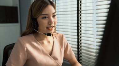 Competent female operator working on computer and while talking with clients. Concept relevant to both call centers and customer service offices.