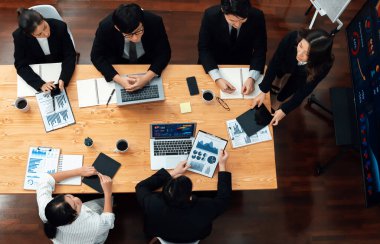 Top view manager or office worker give presentation in harmony conference room to business colleague, BI data dashboard on screen and pile of financial analyzed data reports on meeting table.
