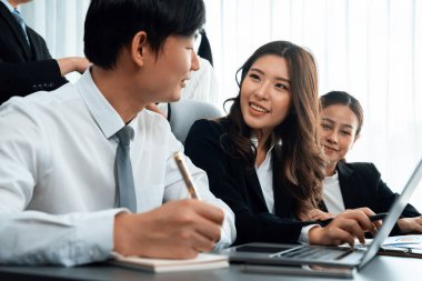 Harmony in office concept as business people analyzing dashboard paper together in workplace. Young colleagues give ideas at manager desk for discussion or strategy planning about project.