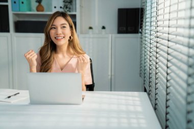 A young female employee receives a promotion, good news or finished her task and overjoyed for being a competent worker.