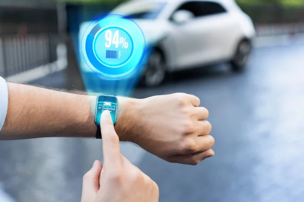 Focus hand touching hologram smartwatch display electric vehicle battery with background of residential charging station at apartment condo. Progressive lifestyle with EV car and smart technology