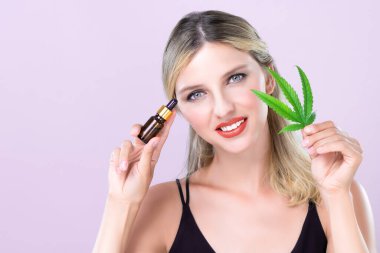 Mükemmel makyajlı güzel bir kadının çekici portresi yeşil yaprak, cilt bakımı ürünü için marihuana özlü şişe. Kozmetik ve güzellik için pembe izole edilmiş arka planda esrar CBD yağı