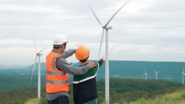 Oğluyla birlikte kırsal kesimdeki bir tepenin tepesinde ya da dağda bir rüzgar çiftliğinde mühendis. Yenilenebilir ve sürdürülebilir enerjinin gelecekteki üretimi için yenilikçi bir ideal. Rüzgar türbininden enerji üretimi.