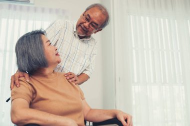 A contented senior couple and their in-home nurse. Elderly female in wheelchair with her young caregiver.