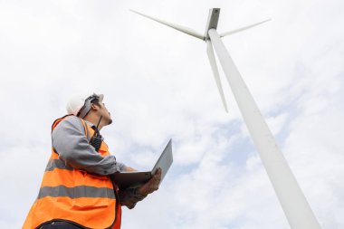 Kırsal kesimdeki bir tepenin tepesinde ya da dağda rüzgar çiftliğinde çalışan bir mühendis. Yenilenebilir ve sürdürülebilir enerjinin gelecekteki üretimi için yenilikçi bir ideal. Rüzgar türbininden enerji üretimi.