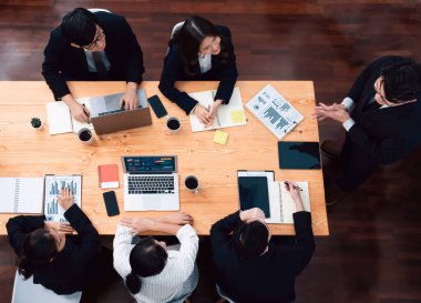 Top view manager or office worker give presentation in harmony conference room to business colleague, BI data dashboard on screen and pile of financial analyzed data reports on meeting table.