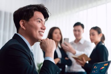 Portrait of focus young successful confident male manager, executive wearing business wear in harmony office arm crossed with blurred meeting background of colleagues, office worker.