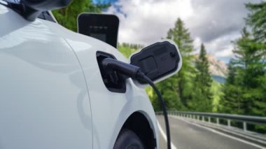 Elektrikli araç konsepti, yeşil çevre için yenilenebilir ve temiz enerjiyle çalışan EV otomobilinin varış noktasına ulaşmadan önce ormandaki şarj istasyonunun enerjisini şarj etmek için durur..