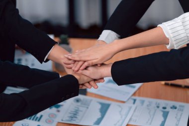 Top view closeup business team of suit-clad businesspeople join hand stack together. Colleague collaborate and work together to promote harmony and teamwork concept in office workplace.