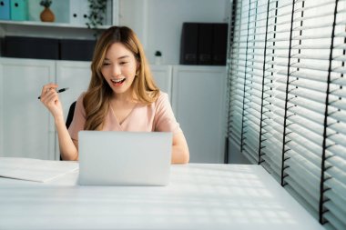 A young female employee receives a promotion, good news or finished her task and overjoyed for being a competent worker.
