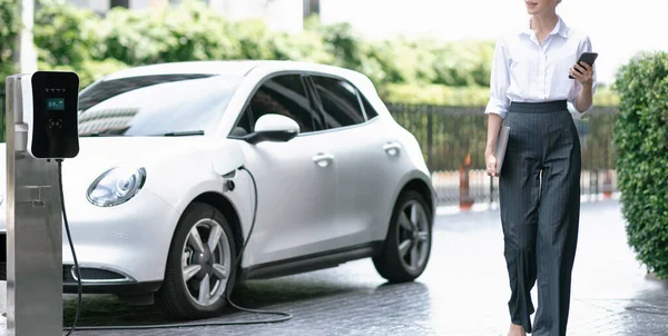 Closeup Businesswoman Using Tablet Walking While Recharging Her Electric Vehicle — Foto de Stock