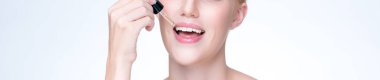 Closeup personable portrait of beautiful woman applying essential oil bottle for skincare product. Cannabis extracted CBD oil dropper for treatment and cannabinoids concept in isolated background.