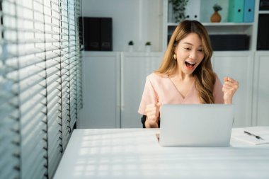 A young female employee receives a promotion, good news or finished her task and overjoyed for being a competent worker.