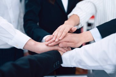 Top view closeup business team of suit-clad businesspeople join hand stack together. Colleague collaborate and work together to promote harmony and teamwork concept in office workplace.