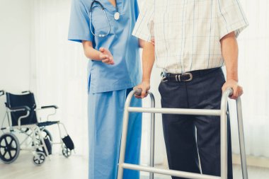 Physiotherapist assists her contented senior patient on folding walker. Recuperation for elderly, seniors care, nursing home.