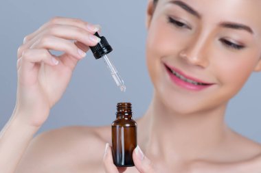 Focus cannabis extracted oil bottle with dropper lid holding by blurred glamorous beautiful asian woman with perfect clean skin and soft smooth makeup in isolated background.