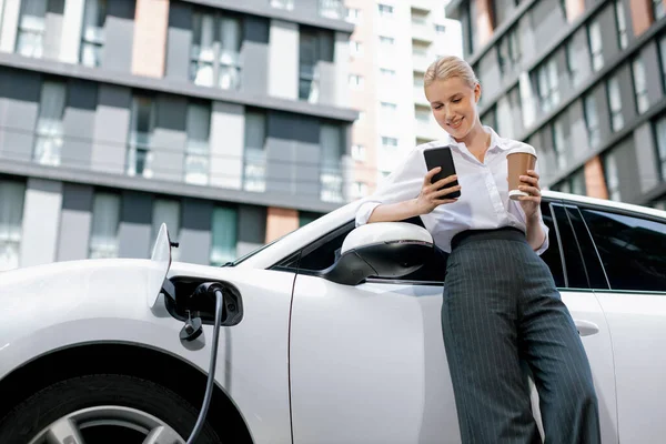Focus Businessman Using Phone Leaning Electric Vehicle Holding Coffee Blurred — Foto Stock