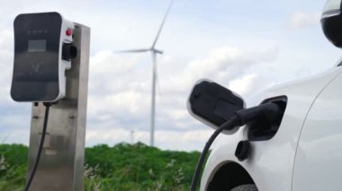Çevreyi korumak için rüzgar türbininden yeşil ve yenilenebilir enerjiyle çalışan şarj istasyonunda şarj edilen gelişmiş gelecek enerji altyapısı konsepti.