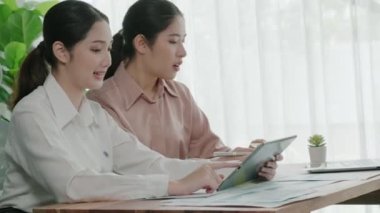 Ofis çalışma alanında birlikte çalışan iki genç hevesli iş kadını. Genç meslektaşlar tartışırken ve dizüstü bilgisayar kullanırken. Modern ofis çalışanları masada birlikte oturuyorlar..