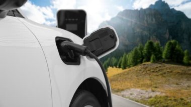 Elektro jeneratör sürücüsüyle enerji sürdürülebilir araba gücü, şarj istasyonunda şarj edilen batarya, ilerici seyahat konsepti için dağ zeminine sahip. Temiz ortamın sembolü olarak doğadaki EV otomobil.