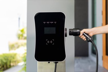 Yakından EV şarj prizi takın, EV araba için yeşil enerjili şarj noktası kavramı aşamalı ev şarj istasyonu garajına bağlı. Çevre dostu şarj edilebilir araba..