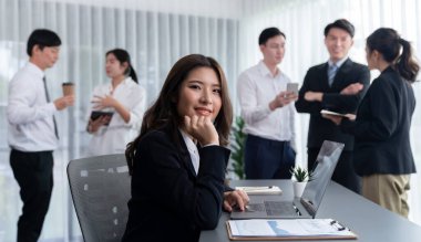 Focus portrait of female manger, businesswoman in the harmony meeting room with blurred of colleagues working together, analyzing financial paper report and dashboard data in background.