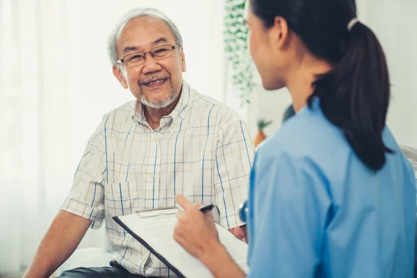 Young Female Doctor Inquires Personal Information Contented Senior Home Medical — Stockfoto