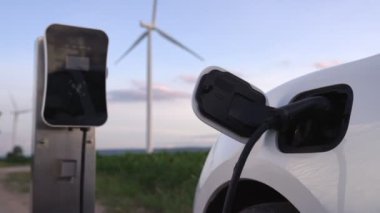 Çevreyi korumak için rüzgar türbininden yeşil ve yenilenebilir enerjiyle çalışan şarj istasyonunda şarj edilen gelişmiş gelecek enerji altyapısı konsepti.